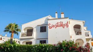 En vit byggnad med balkonger och en skylt med texten ”SiestaMar!”.