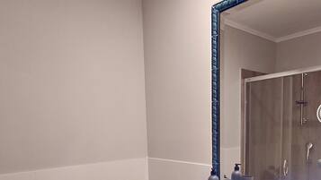 Een badkamer met een wit toilet, een wastafel met een blauwe spiegel en een douchecabine.