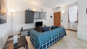 Quarto moderno com cama, mesa de cabeceira, luminária, TV e guarda-roupa.