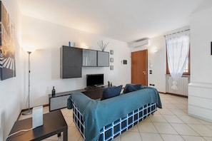 A modern bedroom with a bed, bedside table, lamp, TV, and a wardrobe.