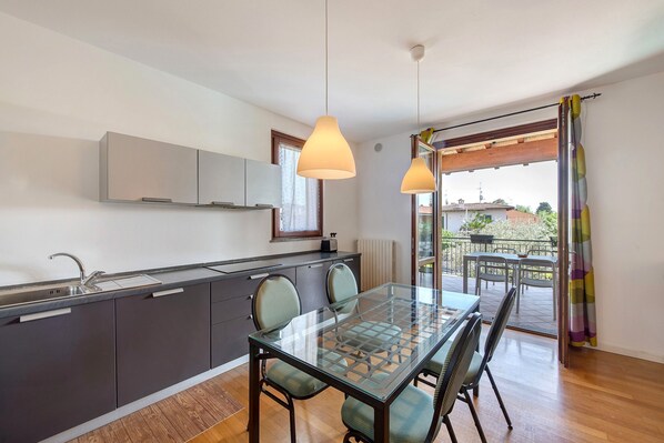 Una cocina moderna con mesa de comedor de vidrio, armarios grises e iluminación colgante.