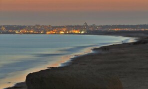 A coastal cityscape at dusk with a beach in the foreground. - Apartment 'Cozy Beach' with Sea View, Balcony and Wi-Fi (Armação de Pêra)