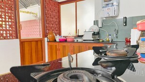 A kitchen with a gas stove, wooden cabinets, and a view of a room with a decorative screen. - Domestay with Mountain View - Gateway of Munnar (Munnar)