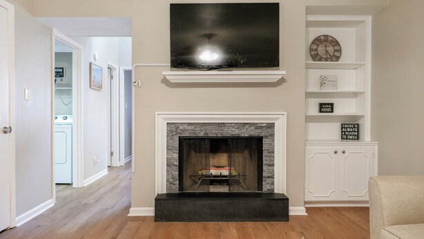 A living room with a fireplace, a mounted TV, and a bookshelf.