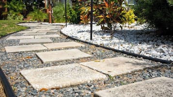 Un vialetto in giardino con pietre di passaggio, circondato da ghiaia e piccole piante.