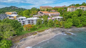 Un hotel costero con varias edificaciones, una playa y vegetación circundante.