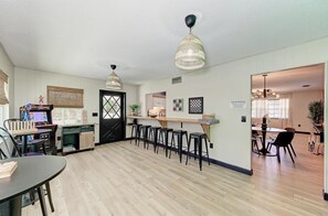 A modern kitchen with a black door, wooden flooring, and bar stools. - 6mi to AMI | Heated Pool • Game Room • Gym (Bradenton)