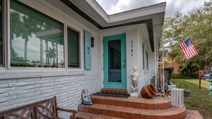 Un edificio blanco con una puerta turquesa, número 1701, y una pequeña estatua en los escalones.