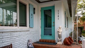 Una casa con una puerta turquesa, un buzón y el número 1701 en la pared.