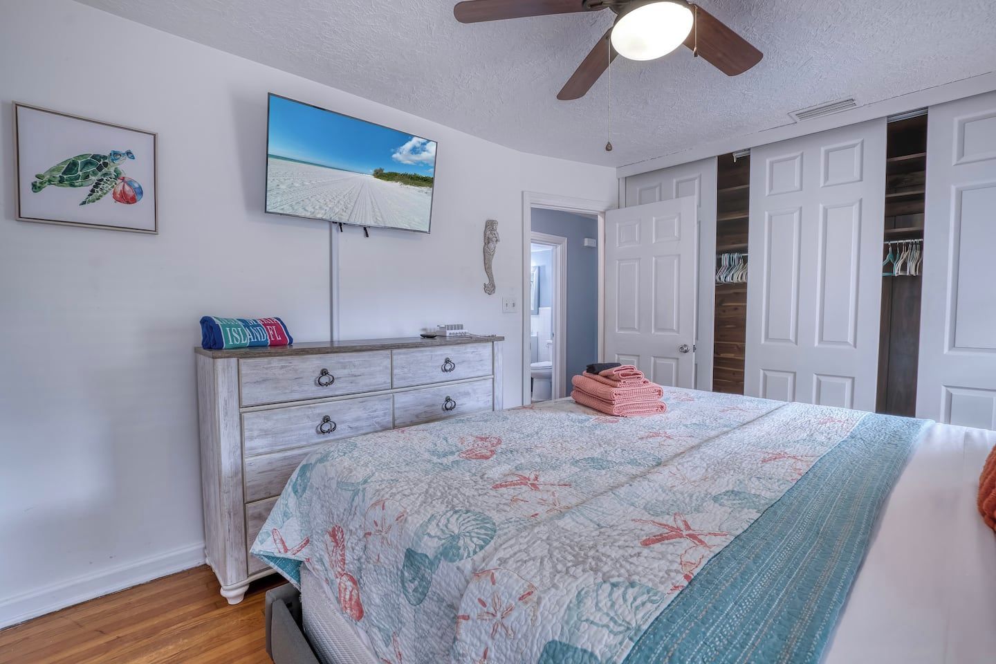 Een slaapkamer met een bed, een dressoir, een televisie en een kast.