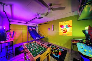 A room with a foosball table, a slide, and a poster of Pac-Man.