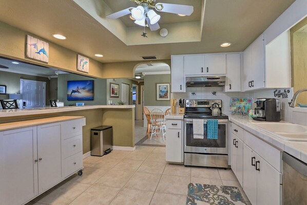A modern kitchen with a central island, stainless steel appliances, and a ceiling fan.