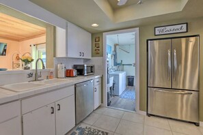 A modern kitchen with white cabinets, stainless steel appliances, and a 'Blessed' sign above the refrigerator.