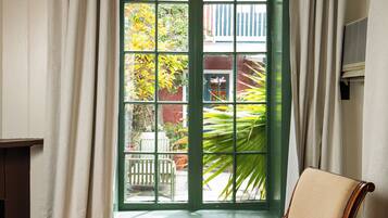 A room with a green-framed window, a wooden chair, and a round table with a patterned surface.