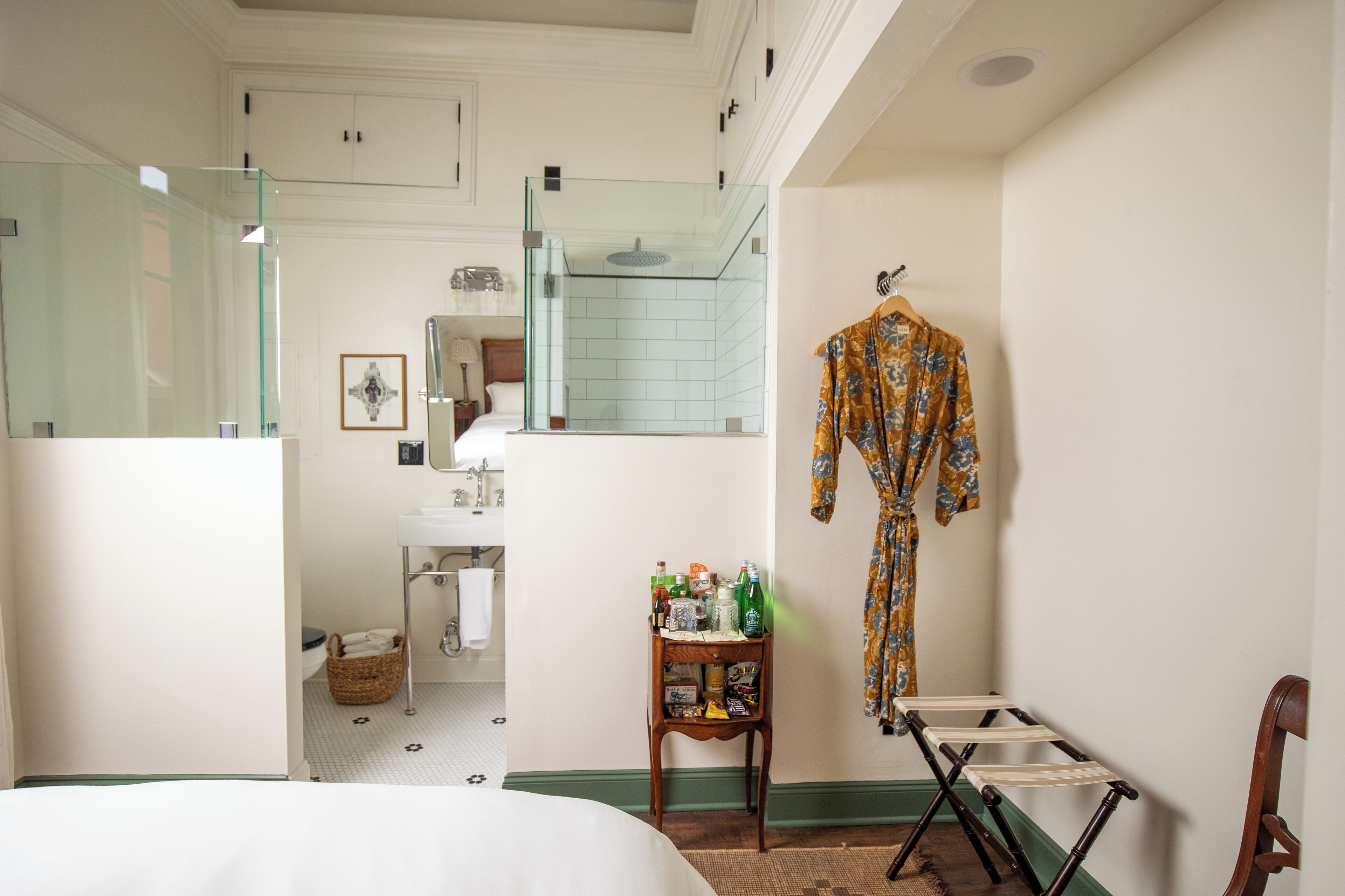 A hotel bathroom with a glass shower enclosure, a sink, and a mirror.