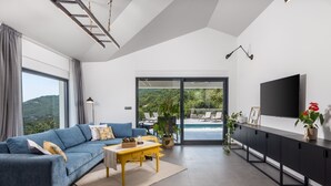 Ein modernes Wohnzimmer mit einem blauen Sofa, einem gelben Couchtisch und einem großen Fernseher auf einem schwarzen Schrank.