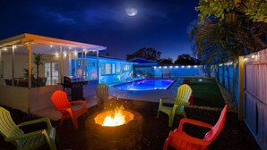Un jardin avec une piscine, un espace salon extérieur et un foyer.