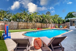A backyard with a swimming pool, lounge chairs, and a wooden fence. - SALTWATER Heated Pool-Putt Putt-AMI-IMG-Game Night-Movies-Gym (Bradenton)