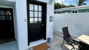 Un edificio bianco con una porta nera, il numero 3, e una piccola area esterna con un tavolo e sedie.