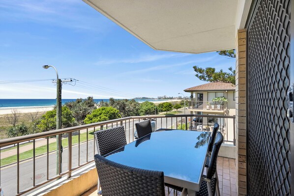 A balcony with a table and chairs, overlooking a beach and ocean. - Beachfront Relaxing Getaway (Bilinga)