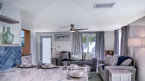 A modern kitchen with a marble countertop, a dining area with a sofa and a side table, and a ceiling fan. - Recover by the Seas at Solace East - prvt pool (Holmes Beach)