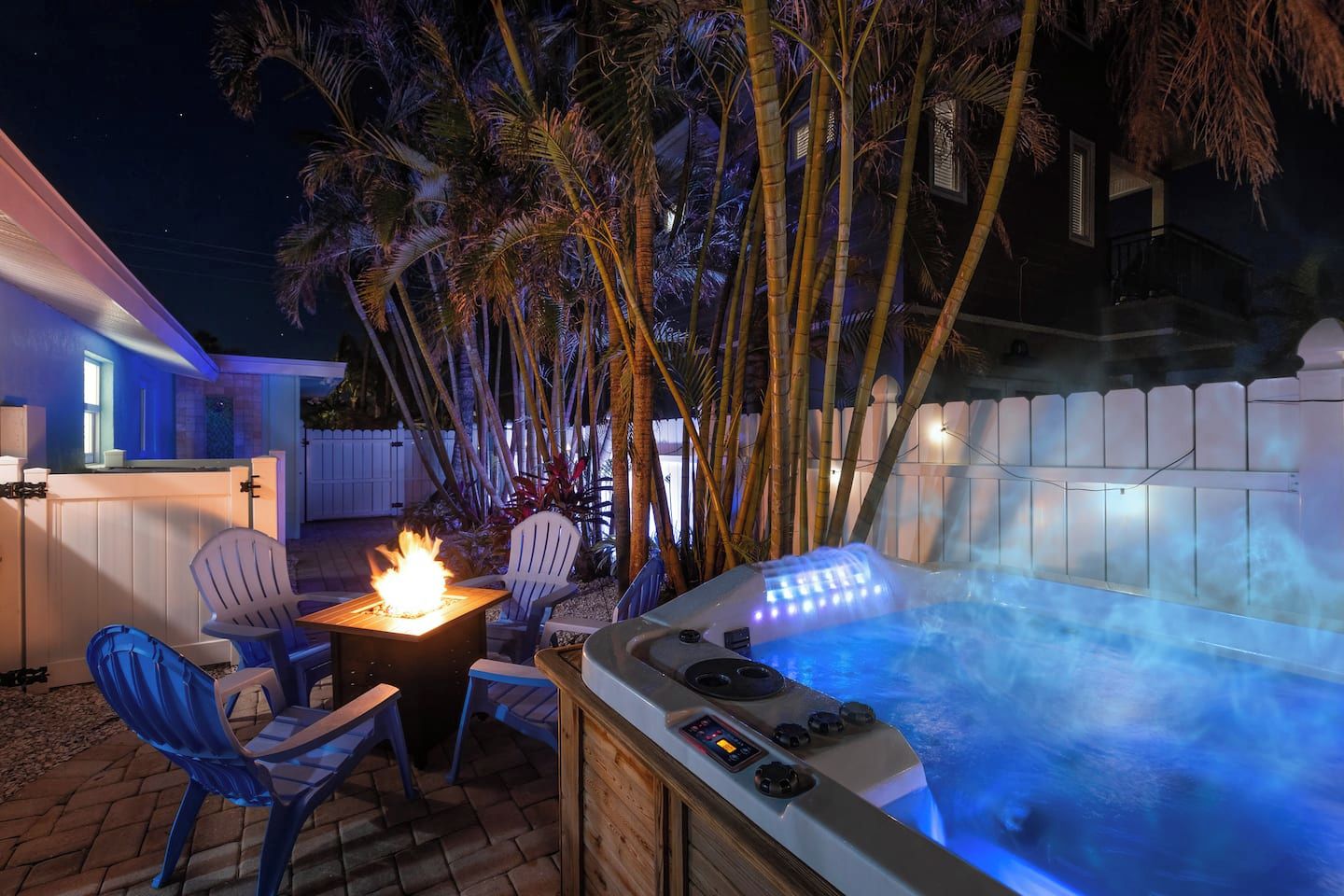 A hot tub with a control panel, surrounded by chairs and a fire feature.
