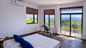Une chambre avec un grand lit, un bureau et un balcon avec vue.