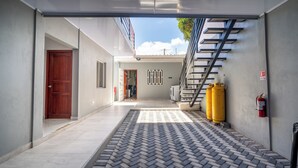 A covered outdoor area with a tiled floor, a wooden door, a staircase, and a fire extinguisher. - Spacious 5-bedroom house in welcoming Managua with WiFi, AC (Managua)