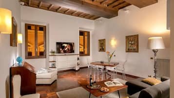 A modern living room with a wooden ceiling, a white sofa, a dining table with chairs, and a television.