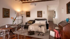 A hotel room with a bed, a desk with a lamp, a chair, a table, and a dresser. - Riccardo Condotti Suite (Rome)