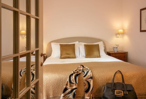A hotel room with a bed, a nightstand, and a lamp. - Riccardo Condotti Suite (Rome)