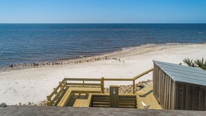 Una terraza de madera que da a una playa con vista despejada al océano.
