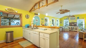 Une cuisine avec des meubles en bois, un évier et un grand îlot central. Une fenêtre offre une vue sur l’extérieur.