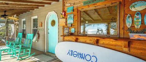 A beach-themed restaurant with turquoise chairs, a surfboard sign, and wooden decor.