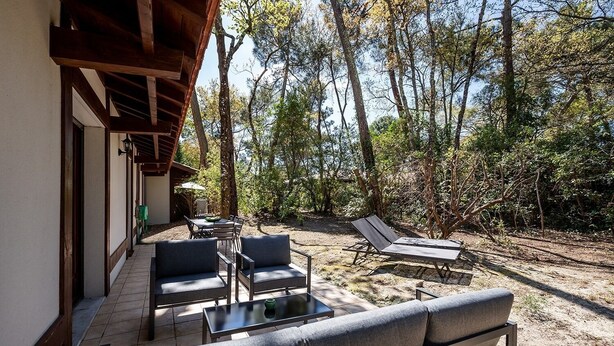 An outdoor patio with a dining table, chairs, and a lounge area with a chair and a table. - Villas Indigo, Villa(s) Indigo proches des plages (La Teste-de-Buch)