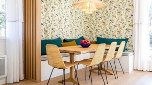 A dining area with a wooden table, wicker chairs, and a bowl of fruit. - Villas Indigo, Villa(s) Indigo proches des plages (La Teste-de-Buch)