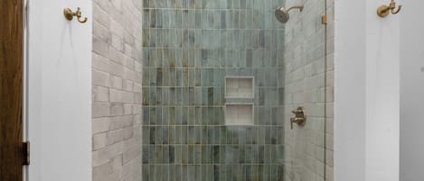 Ducha con puerta de vidrio, cabezal de ducha de mano y grifo empotrado.