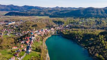 An aerial view of a lakeside town with houses, a church, and a bridge.