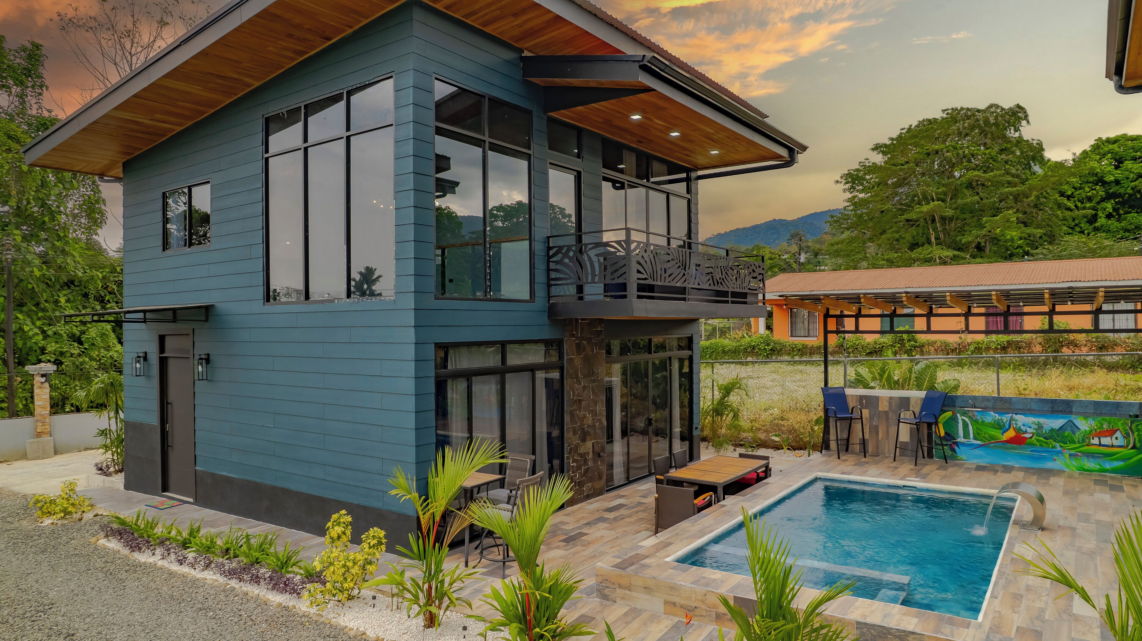 Une maison moderne à deux étages, dotée d’un grand balcon, d’une piscine et d’un jardin.
