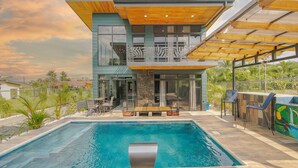 A modern two-story house with a swimming pool, outdoor seating, and a view of the surrounding landscape. - Casa Azulada-King beds, pool, BBQ, parking on property, 5 min to LaFortuna! (La Fortuna)