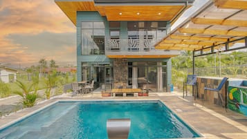 Une maison moderne à deux étages, dotée d’une piscine, d’un espace extérieur aménagé et offrant une vue sur le paysage environnant.