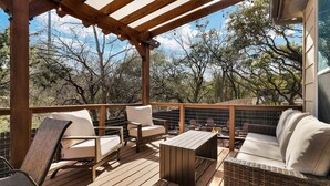 A wooden deck with outdoor furniture, including chairs and a sofa, overlooking a natural landscape.