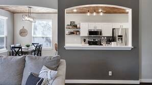 A modern kitchen with white cabinets, stainless steel appliances, and a wooden ceiling.
