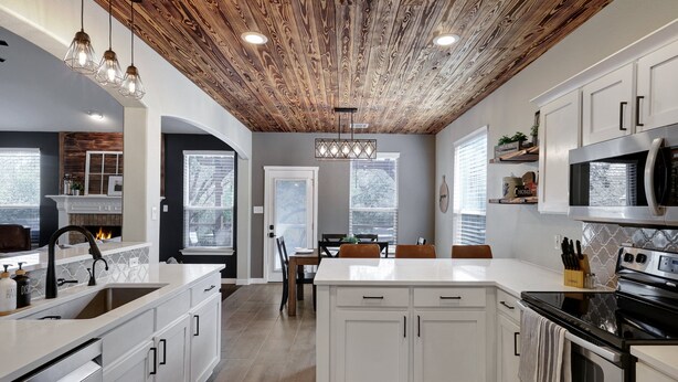 A modern kitchen with white cabinetry, a wooden ceiling, and a central island.