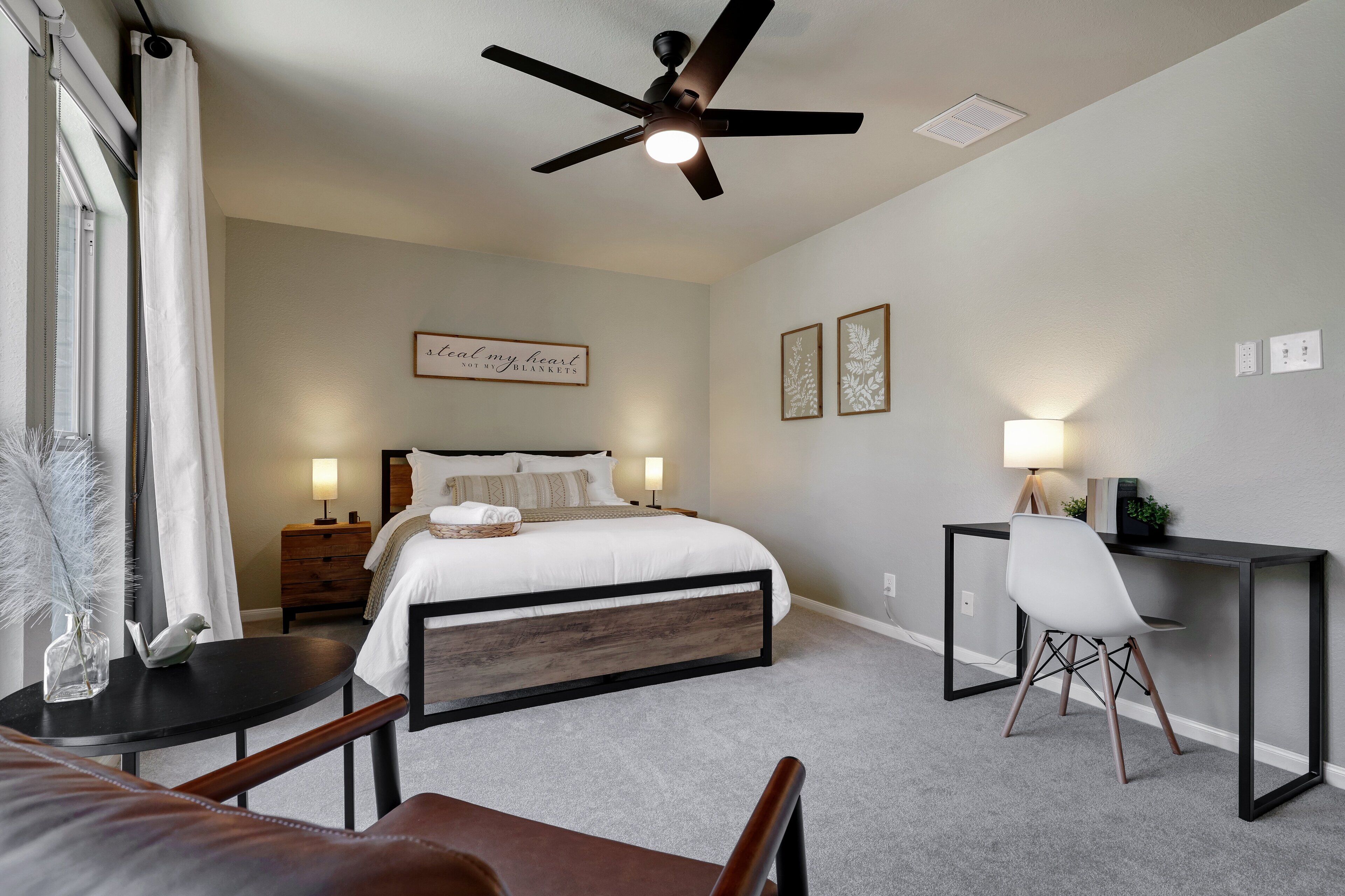 A bedroom with a bed, bedside tables, a desk, and a chair.