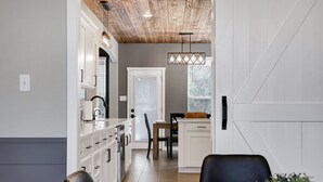 A modern kitchen with white cabinetry, a wooden ceiling, and pendant lighting.