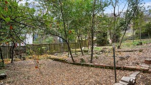 Un jardín con árboles, una cerca de madera y un camino de piedra.