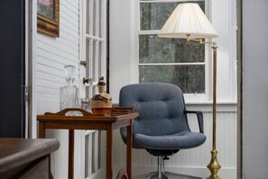 Una habitación con una silla, una lámpara y una mesa con una botella y vasos.