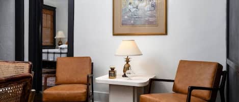 Una habitación con dos sillones de cuero marrón, una mesita blanca con una lámpara y un cuadro en la pared.