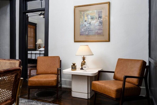 Una habitación con dos sillones de cuero marrón, una mesita blanca con una lámpara y un cuadro en la pared.